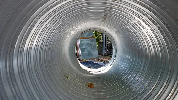 Aluminum duct silver Peek inside. Industrial equipment can be seen through the perforated metal pipe. Manufacture of iron pipes. — Stock Photo, Image