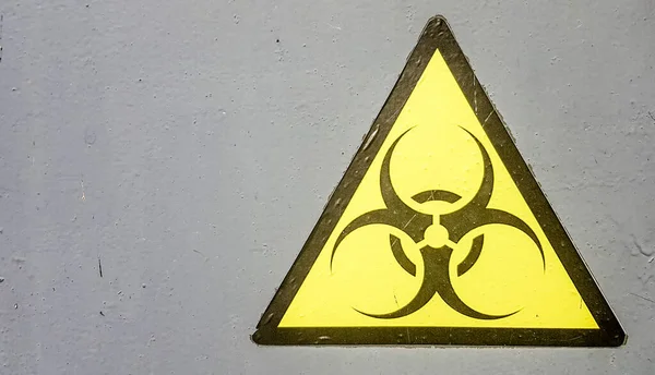 Biohazard Zeichen Symbol Biohazard Warnung, schwarz gelbes Dreieck Beschilderung Makro auf grauer Metallwand — Stockfoto