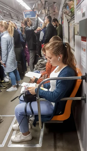 Ukraina, Kiev - 6 oktober 2019: Porträtt av en ung kvinnlig turist i tunnelbanan läser en tidning. Vacker flicka läser en bok i en tunnelbana tåg i en tågbil — Stockfoto