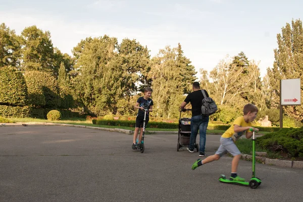 Oekraïne, Kiev - 6 juli 2019: kinderen spelen scooters op straat in het park. Buitenactiviteiten en sporten voor het kind op een veilige woonstraat. Sport voor kleuters — Stockfoto