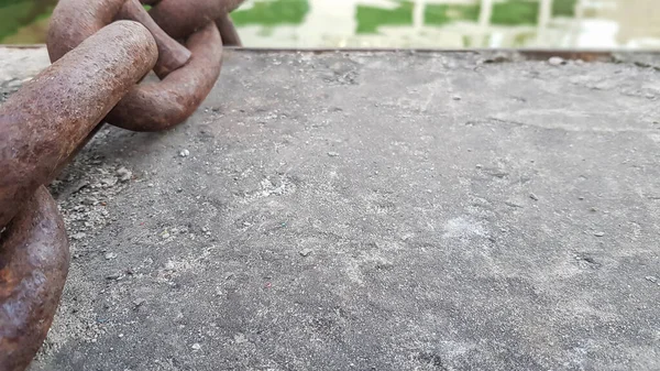 Cadeia de ferro enferrujado em concreto. Correntes âncoras são enterradas em concreto para amarração no porto. Antecedentes com espaço de cópia. Correntes grossas, maciças e enferrujadas em uma superfície rochosa de concreto — Fotografia de Stock