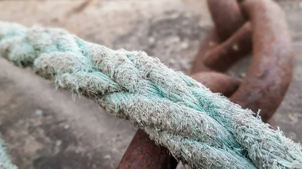 Corda de manila de barco envelhecida de cor azul colocada na estrada de concreto no porto. Doca com cordas e cordas. Pólo de amarração de metal no cais de concreto, foco seletivo — Fotografia de Stock