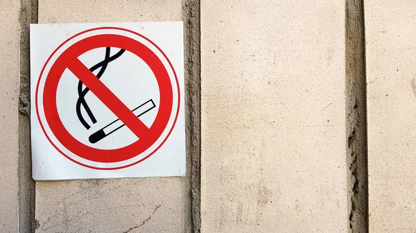 Ein rundes Rauchverbot-Schild in der Stadt. Nichtraucherschilder, die die Wände aller Bereiche überwachen, um den Raucherbereich einzuschränken. rotes und schwarzes Schild mit einem strukturierten grauen Steinhintergrund - Rauchverbot — Stockfoto