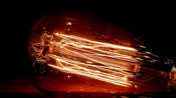 Belysning indretning. Vintage hængende Edison pære på en mørk baggrund. Gamle støvede pærer glødende i mørket. En lampe inde i en dekorativ glaslampe. Lys begynder at dukke op og glød i midten . - Stock-foto