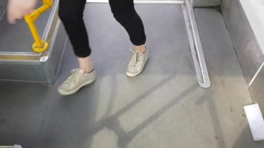 Metro ya da tramvayda yürüyen insanların bacakları. Araba istasyondaki sürgülü kapıları açar ve kapatır. Tren istasyondan hareket etmek üzere. Erkekler ve kadınlar tramvaya biniyor..