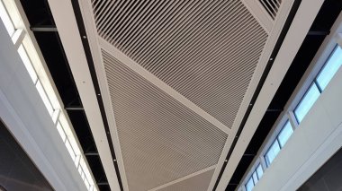 Tavan işi bitti. Beyaz örgü asılmış tavan, ticari binaların iç dekorasyonu. Işıklı bir alışveriş merkezinin tavan arası.