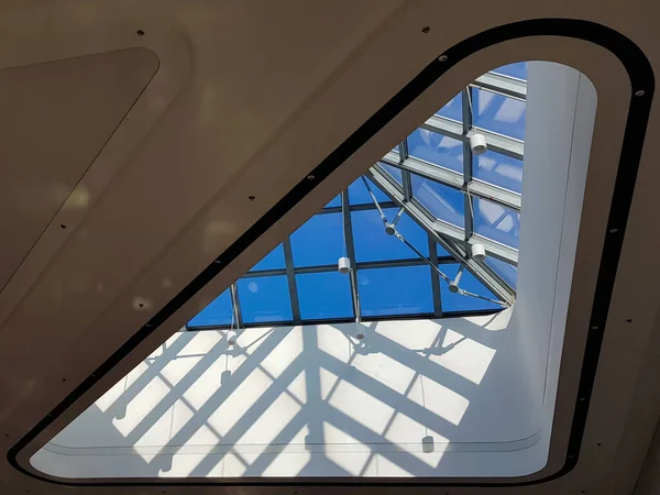 Steel structure roof ceiling made of metal and glass with blue sky background. Modern sleek shopping architecture in mall