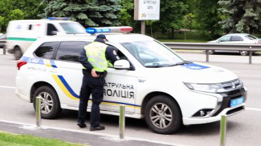 Ukrayna, Kiev - 2 Haziran 2020. Ukrayna 'daki Kiev yollarında polis devriye arabaları güvenliği sağlıyor. Bir erkek polis yolda arabasının yanında duruyor..