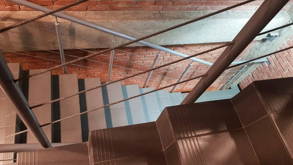 Red brick building with a modern staircase in a loft style with metal railing. Stairs adorn the building. Modern stairwell. Steel railing. Staircase in perspective