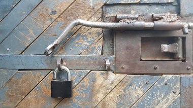 Yıpranmış ahşap kapılı, asma kilit, mandal ve metal teçhizatlı.