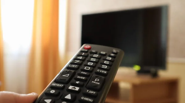 手握电视遥控装置 在电视上播放冲浪节目 打开或关闭电视在客厅或卧室的黑屏床头柜 复制空间 — 图库照片