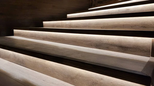 Illuminated staircase with wooden steps and illuminated at night in the interior of a large house.