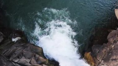 Şelale yukarıdan aşağıya bakıyor. Nehrin üst manzarası, su taşların üzerinden akıyor. Kayalık dağ şelalesi. Hava manzaralı dağ kayası çağlayan nehir akıntısı doğal manzara arkaplan resmi.