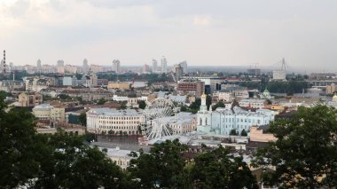Kiev şehrinin Podolsky bölgesinin yüksekliğinden, dönme dolabı olan eski meydandan ve yaldızlı kubbeli çan kulesinden. Yazın güzel şehir manzarası
