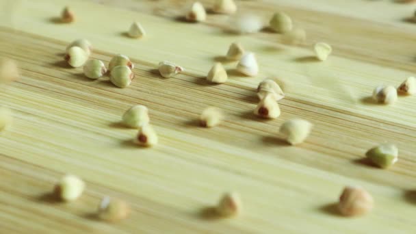 Körner Von Rohem Grünen Buchweizen Fallen Langsam Auf Einen Holztisch — Stockvideo