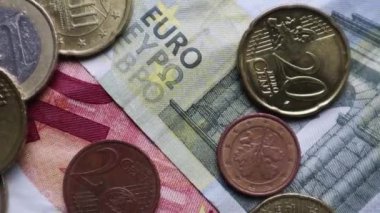 Avro banknotları ve madeni paralar arka plan olarak döner. Dönüşümlü olarak avroya bakarken vuruldu. Bozuk paralar farklı pozisyonlarda üst üste istiflenir. Para kavramı.