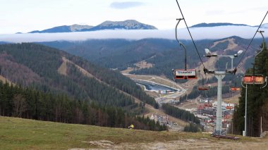 Ukrayna, Bukovel - 20 Kasım 2019. Sonbahar dağ yamaçlarının arka planına karşı bir telesiyej ile kayak merkezinin sonbahar manzarası ve kış kayak merkezinin yapım aşamasındaki altyapısı