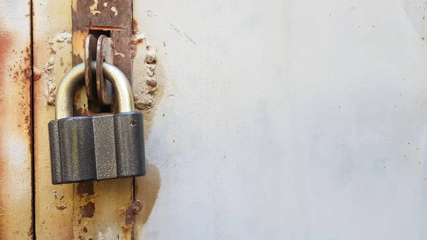 Kapalı asma kilidi olan paslı metal bir kapıya yakın çekim