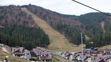 Sonbahar hava manzaralı Bukovel kayak merkezi. Ekolojik kırsal kesimdeki otellerin arka plandaki ladin ağaçları ve dağ tepeleriyle karşılaştırılması. Ukrayna, Bukovel - 20 Kasım 2019