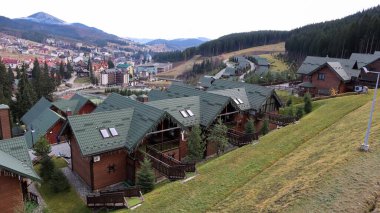Sonbahar hava manzaralı Bukovel kayak merkezi. Ekolojik kırsal kesimdeki otellerin arka plandaki ladin ağaçları ve dağ tepeleriyle karşılaştırılması. Ukrayna, Bukovel - 20 Kasım 2019