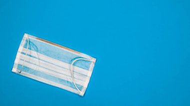 Ağız ve burnu mavi arka planda tutmak için plastik pedli 3 katlı tek kullanımlık cerrahi maske. Bakterilerden, sağlık hizmetlerinden ve tıptan korunma kavramı. COVID-19. Boşluğu kopyala