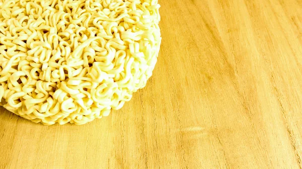 Raw instant noodles on a wooden plate with copy space to add text on the background. pasta, for the preparation of which it is enough to pour boiling water and wait a few minutes