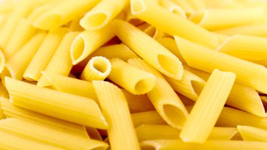 Penne Rigate Raw Pasta, eğimli kesimli ve kaburgalı yüzeyi olan kısa bir makarnadır. Geleneksel İtalyan makarnası. Makarna arka planı. İtalyan yemek malzemeleri üst görünüm