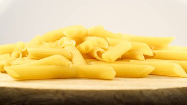Penne Rigate Raw Pasta, eğimli kesimli ve kaburgalı yüzeyi olan kısa bir makarnadır. Geleneksel İtalyan makarnası. Makarna arka planı. Tahta bir tabakta İtalyan yemek malzemesinin yan görüntüsü