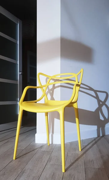 Yellow plastic chair near the wall with a shadow in the interior of the house