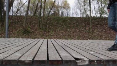 Sonbahar havasında bir gölün üzerinde tahta bir köprüde botlar, kot pantolon ve ceketle yürüyen bir kadın. Endişe etmeden neşeli, mutlu bir yolculuk. Rahatlama, doğadaki hayatın tadını çıkarma, düşük görüş açısı..