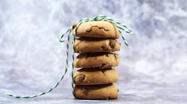 Amerikan çikolatalı kurabiyeleri üst üste yığılmış gri arka planda yeşil iplikle. Geleneksel yuvarlak çikolatalı hamur. Fırın. Tatlı nefis, hamur işleri.