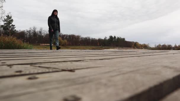 Kobieta Spacerująca Butach Dżinsach Kurtce Drewnianym Moście Nad Jeziorem Jesienną — Wideo stockowe