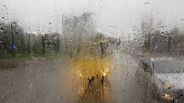 Rain on the rear window of a car in autumn. Inside view of the road with moving cars in the city through the window from the car with rain drops. driving a car in the field of view of the rear window