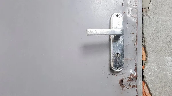 Eski bir kapının eski metal kapı tokmağı. Kapı kolunda pas var.