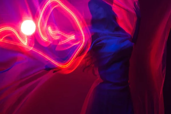 Kulüpte çekici dans eden kız, neon ışık, hareket efektleri. Siyah arka plan, uzun pozlama