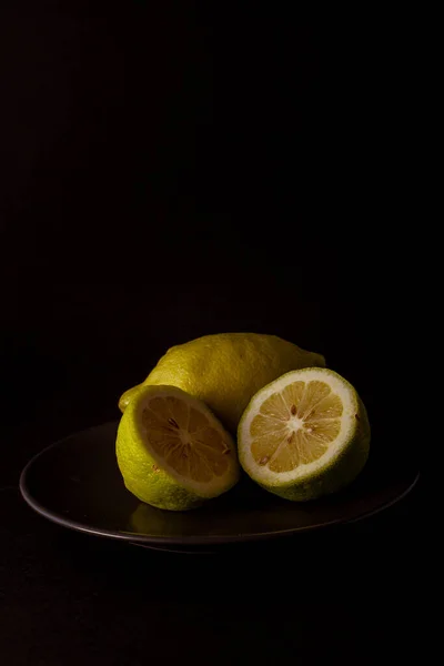Fresh seasonal lemon cut on a black plate on a black background