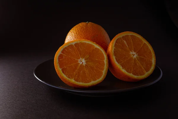 fresh cut oranges on a black plate on a black background