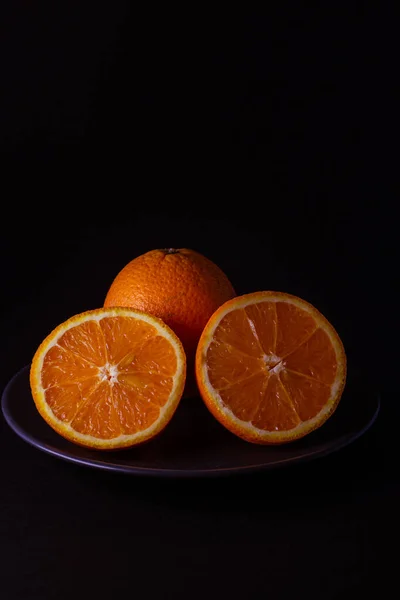 fresh cut oranges on a black plate on a black background