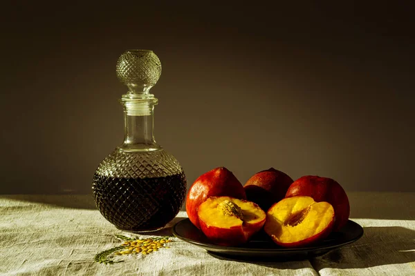 新鲜的红桃子和黑色底色的玻璃瓶白兰地 — 图库照片
