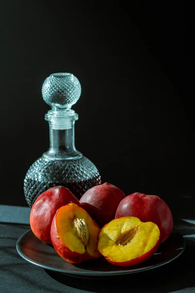新鲜的红桃子和黑色底色的玻璃瓶白兰地 — 图库照片