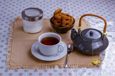 Bir fincan siyah çay, şeker tenceresi, limon ve kurabiye kırsal masa arka planında.