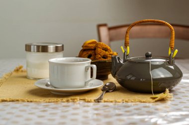 Bir fincan siyah çay, şeker tenceresi, limon ve kurabiye kırsal masa arka planında.