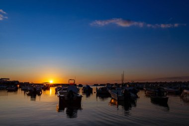 Deniz üzerinde gün batımının güzel manzarası ve marinada yatlar.