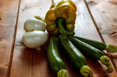 Bahçeden taze sebzelerle, ahşap masada soğan, kabak ve sarı biberle dolu bir hayat..