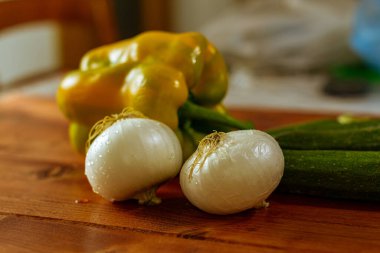 Bahçeden taze sebzelerle, ahşap masada soğan, kabak ve sarı biberle dolu bir hayat..