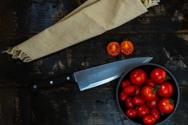 Taze kırmızı, yeşil ve sarı domateslerle dolu bir hayat. Tahta masa ve mutfak bıçağının bahçesinden yeni toplanmış.