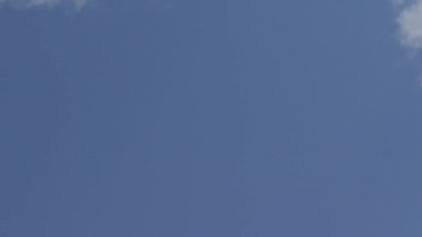 Yazın açık mavi gökyüzüne doğru hızla hareket eden beyaz bulutların hızlandırılmış videosu