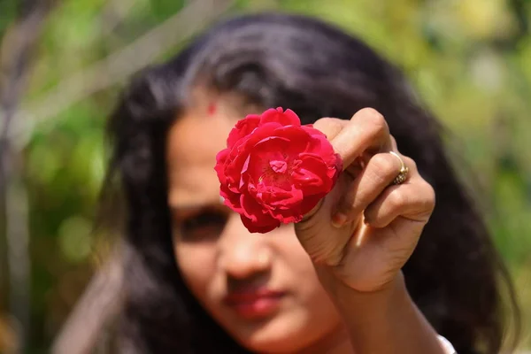 開いた髪に赤いバラの花を与える若い女の子のぼやけた顔 — ストック写真