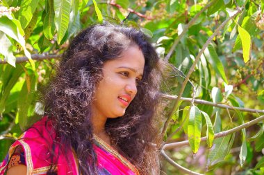 Bahçedeki dağınık saçlı güzel bir kızın yan görüntüsü.