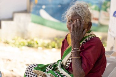 Chennai - Tamilnadu Hindistan. 24 Temmuz 2020. Elleri ağzında oturan yaşlı bir kadın, açık havada kadın portresi.